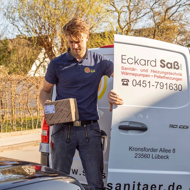 Mitarbeiter holt ein Päckchen aus dem Firmenwagen